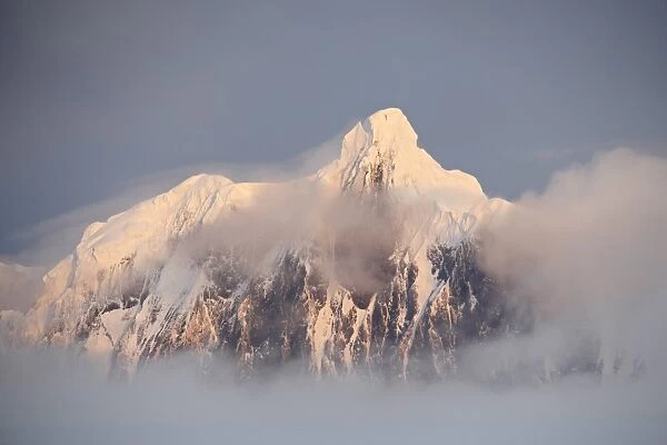 Snow covered mountain at sunset, generating its own fog cover, Wiencke Island