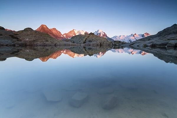 Snowy peaks reflected in the alpine lake at sunset, Fuorcla, Surlej, St