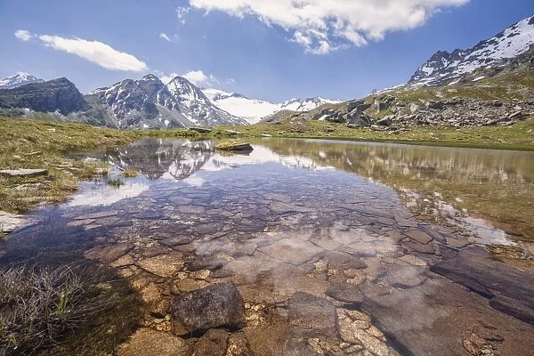 The snowy peaks are reflected in the clear waters of Lake Piz, La Margna, Fedoz Valley