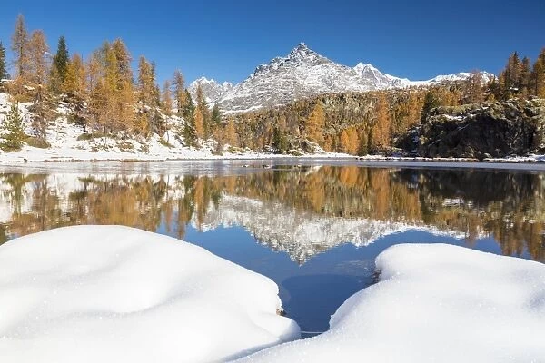 The snowy peaks are reflected in the frozen Lake Mufule, Malenco Valley, Province of Sondrio