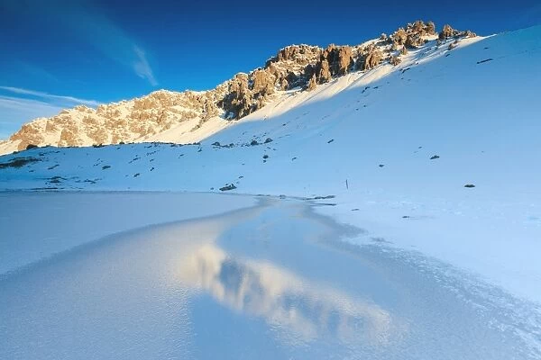 Snowy peaks reflected in the icy Lake, Piz Umbrail at dawn, Braulio Valley, Valtellina