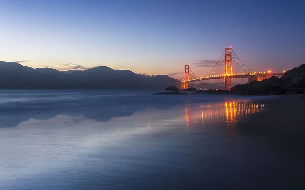 Soft flowing water reflects the beautiful Golden Gate Bridge from Baker Beach, San Francisco