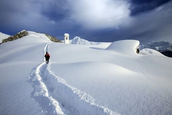 A solitary hiker leaving the little village at the Scima Alp covered in snow, Valchiavenna, Lombardy, Italy, Europe