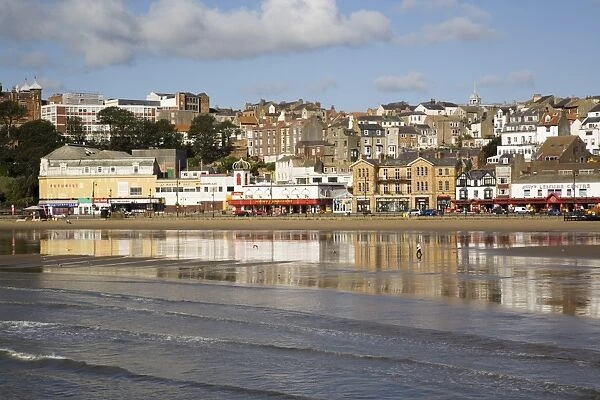 South Sands in South Bay at low tide with seafront buildings reflected in wet sand on beach