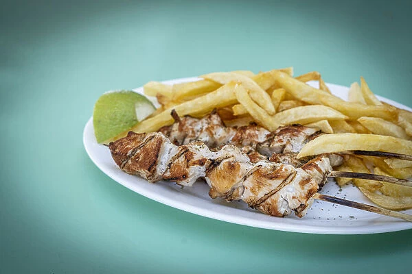 Souvlaki, popular Greek food consisting of small pieces of meat grilled on a skewer served with french fries, Greek Islands, Greece, Europe