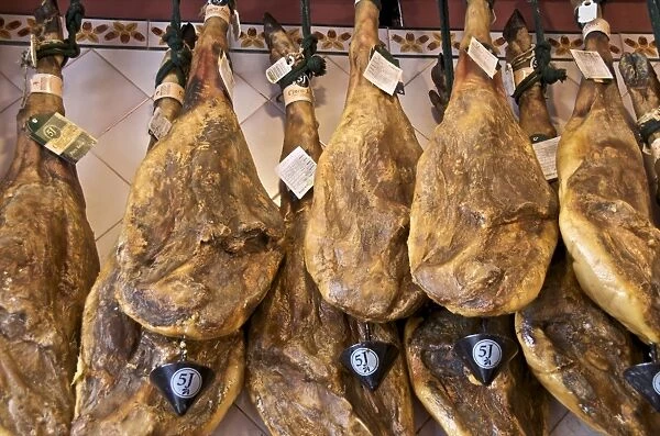 Spanish hams hanging in a restaurant bodega, Seville, Andalusia, Spain, Europe
