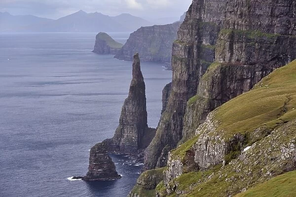 Spectacular 300-400m high cliffs on west coast of Sandoy, Oknadalsdrangur sea stack in foreground