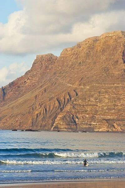 Spectacular 600m volcanic cliffs of the Risco de Famara rising over Lanzarotes finest surf beach at Famara in the north west of the island, Famara, Lanzarote, Canary Islands, Spain, Atlantic