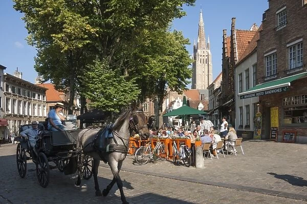 Square with cafe, horse and carriage, and spire of Church of Our Lady, Bruges, Belgium