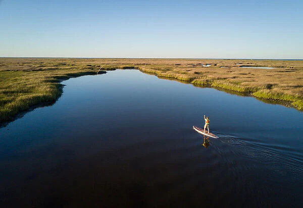 Stand up paddle boarder paddles through a Chesapeake Bay salt marsh near Hampton