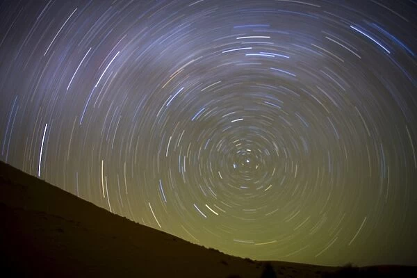 Star trails captured using an exposure time of two hours to record the rotation of the earth on its Polar Axis, stars are rotating around the Pole Star (Polaris), the Sahara Desert near Merzouga, Morocco, North