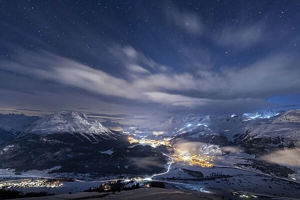 Starry winter sky over St. Moritz village and Upper Engadine covered with snow viewed
