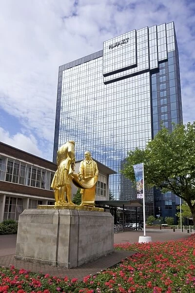Statue of Boulton, Watt and Murdoch, nicknamed The Golden Boys or The Carpet Salesmen by William Bloye, with Hyatt Hotel from Centenary Square, Birmingham city centre, West Midlands, England, United