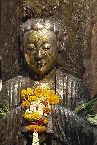 Detail of statue with offering of marigold flowers
