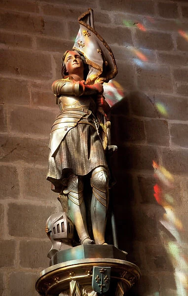 Statue of St. Joan of Arc with coloured light from stained glass, Church of Notre Dame