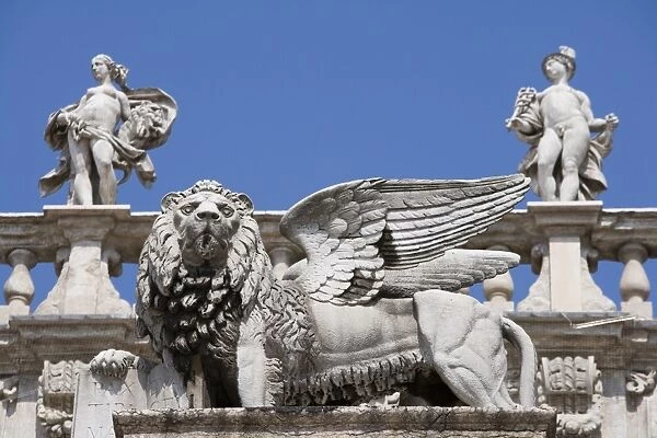 Statue of winged Venetian lion in front of statues of Venus and Mercury on the top of the Palazzo Maffei, Verona, Veneto