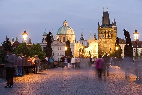 Statues and crowds on the Charles Bridge, with the dome of the Church of St