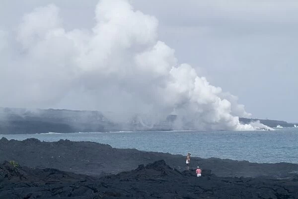 Steam plumes from hot lava flowing onto the beach and