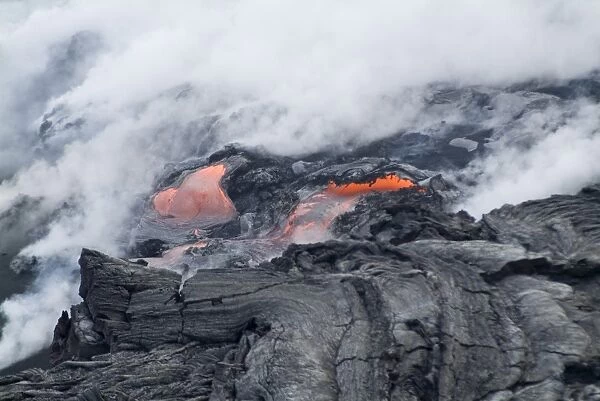 Steam plumes from hot lava flowing onto beach and into the ocean