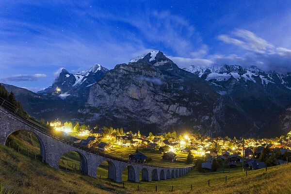Steep viaduct of funicular above the illuminated village of Murren at night