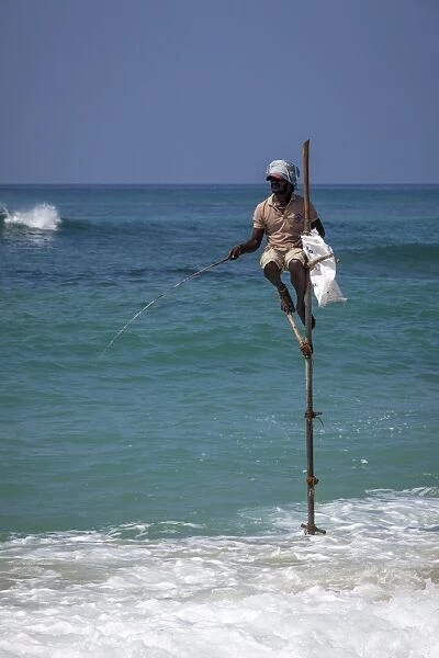 Stilt fisherman using traditional fishing techniques on a wooden pole, Weligama, Sri Lanka, Indian Ocean, Asia