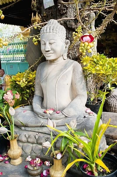 Stone Buddha statue covered in flowers at The Royal Palace, Phnom Penh, Cambodia, Indochina, Southeast Asia, Asia
