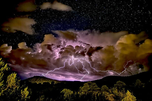 A storm approaching Sullivan Butte in Chino Valley at night with a starry sky above