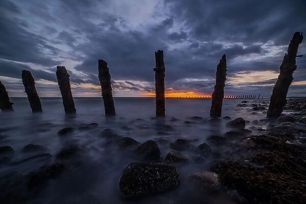 Storm clouds gather over the Irish Sea, worn sea defences from South Walney at sunset from the Cumbrian Coast, Cumbria, England, United Kingdom, Europe