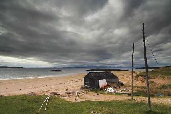 Stormy sky with fishermans hut and net drying poles, Redpoint beach