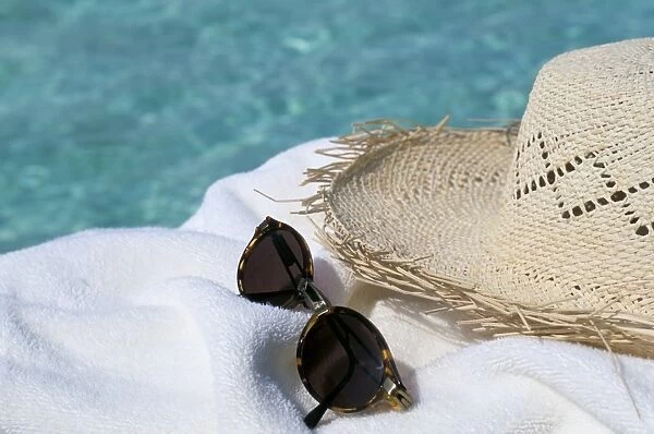 Straw hat and sunglasses on towel