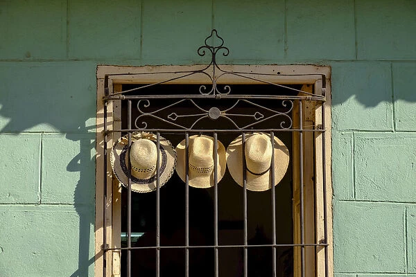 Three straw hats hang on an iron grate in a window, Trinidad, Cuba, West Indies