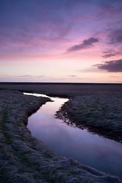 Stream meandering into the distance and reflecting colours in the twilight sky