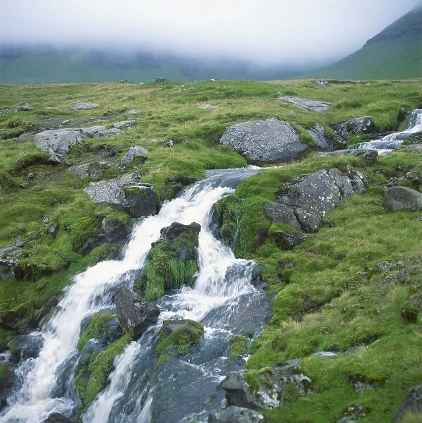 Stream rushing over rocks in a wet misty environment, Estoroy Island, Faroe Islands