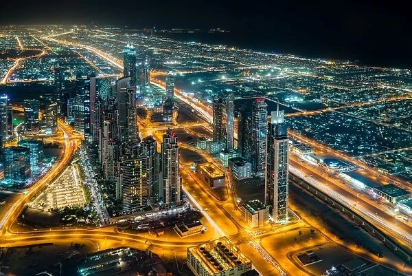 The street lights and skyscrapers of Dubai are seen at night from high above the city