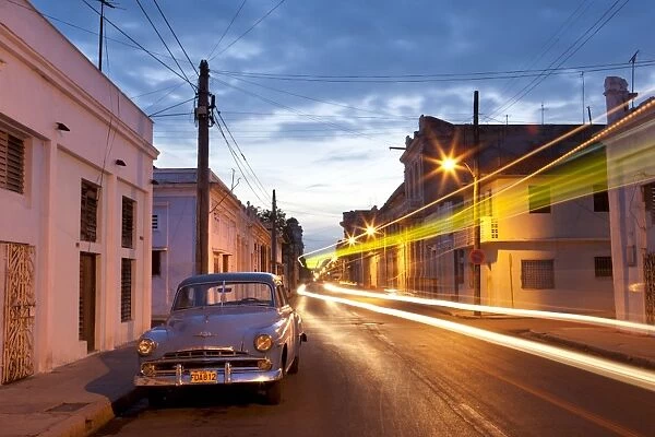 Street scene at night showing Classic American car and the light trails of passing traffic