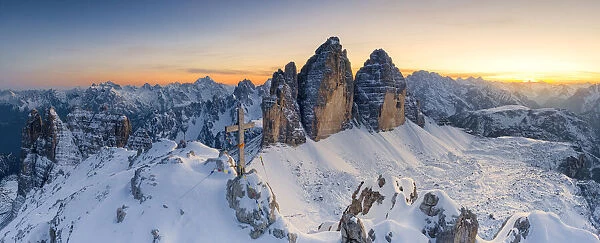 Summit cross on snow capped Monte Paterno with Tre Cime Di Lavaredo in background at