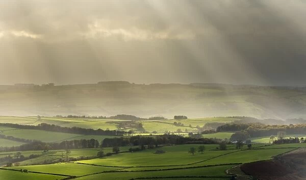 Sun illuminating fields in rural landscape in November, near Baslow, seen from Baslow Edge
