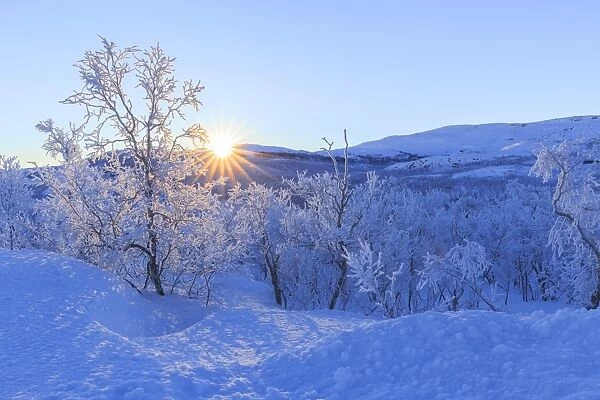The sun rises from the peaks on the border of Sweden and Norway, Riskgransen, Norbottens Ian