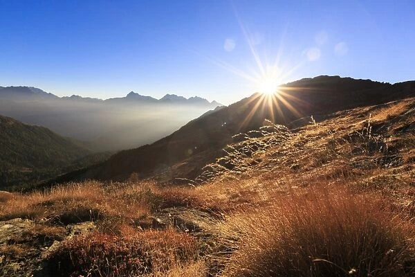 Sunbeams on alpine pastures with peak Scalino in the background, Val Torreggio, Malenco Valley