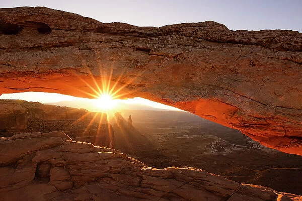 Sunlight envelops the Canyonlands Valley during a summer sunrise, framed by Mesa Arch, Utah, United States of America, North America