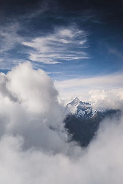 Sunlight over Weisshorn peak emerging from a sea of clouds, canton of Valais, Switzerland