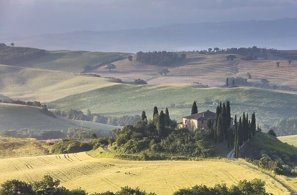 Sunrise on the gentle green hills and typical farm house of Val d Orcia, UNESCO World Heritage Site