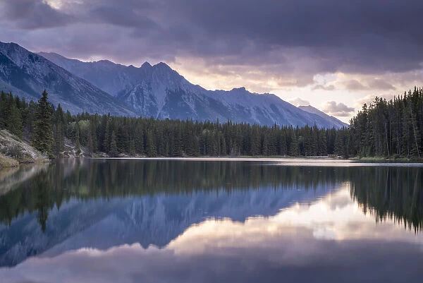Sunrise over the mountains of the Rockies, reflected in Johnson Lake, Banff National Park