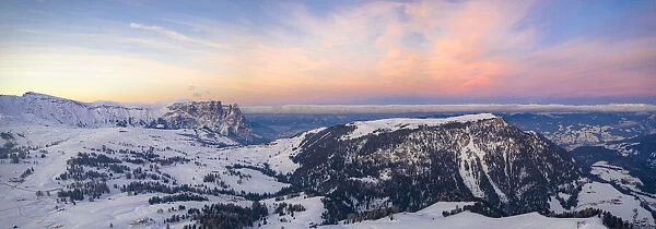 Sunrise over Sciliar Massif and Compatsch village covered with snow, aerial view