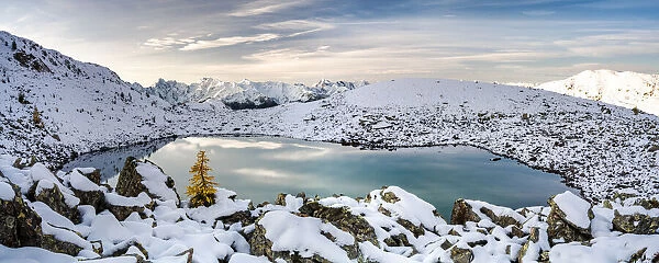 Sunrise over the snowcapped Orobie Alps and frozen lake Rogneda during a cold autumn