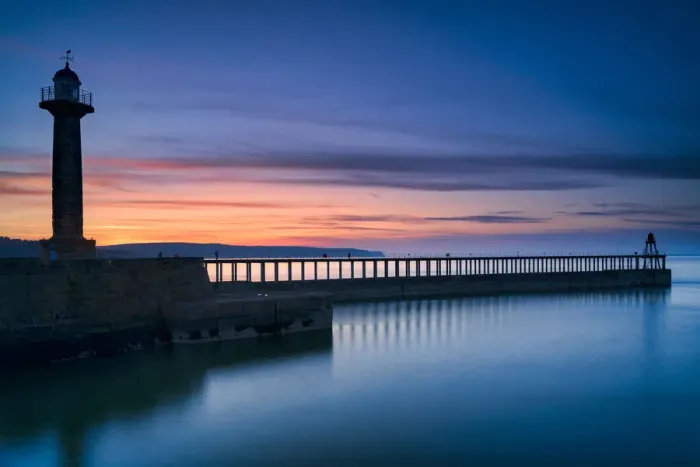 Framed Print : Sunset afterglow over Whitby West Pier and lighthouse, the North Yorkshire coast
