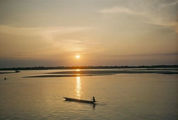 Sunset over Araguava River, Bananal and Karaja Indian in canoe, Brazil, South America