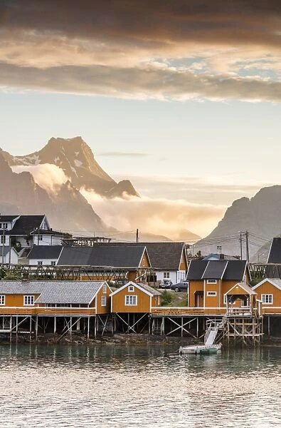 Sunset on the fishing village framed by rocky peaks and sea, Sakrisoya, Nordland county