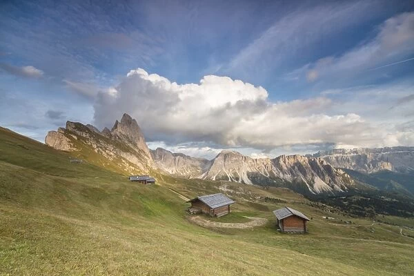 Sunset on the green meadows and huts of the Odle mountain range seen from Seceda