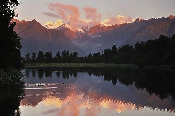 Sunset, Lake Matheson, with Mount Tasman and Mount Cook behind clouds, Westland Tai Poutini National Park, UNESCO World Heritage Site, West Coast, Southern Alps, South Island, New